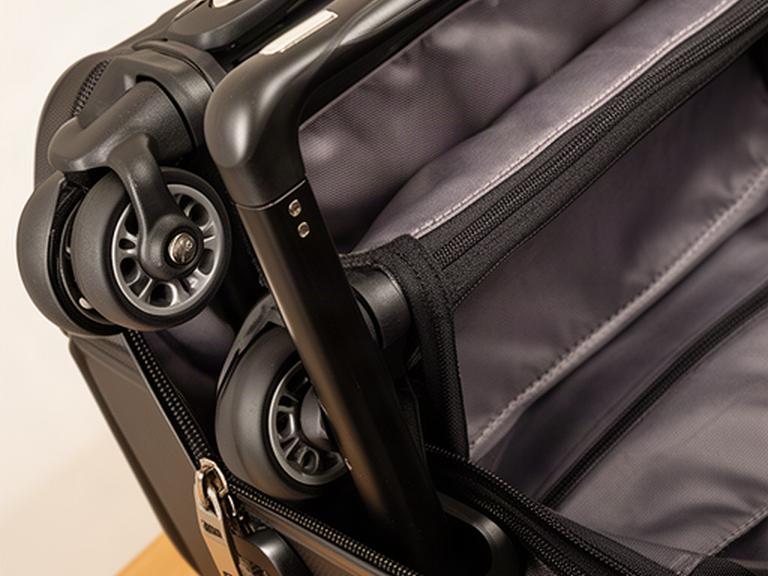 Detailaufnahme von Rollen, Teleskopgriff und Innenfutter eines schwarzen Reisekoffers